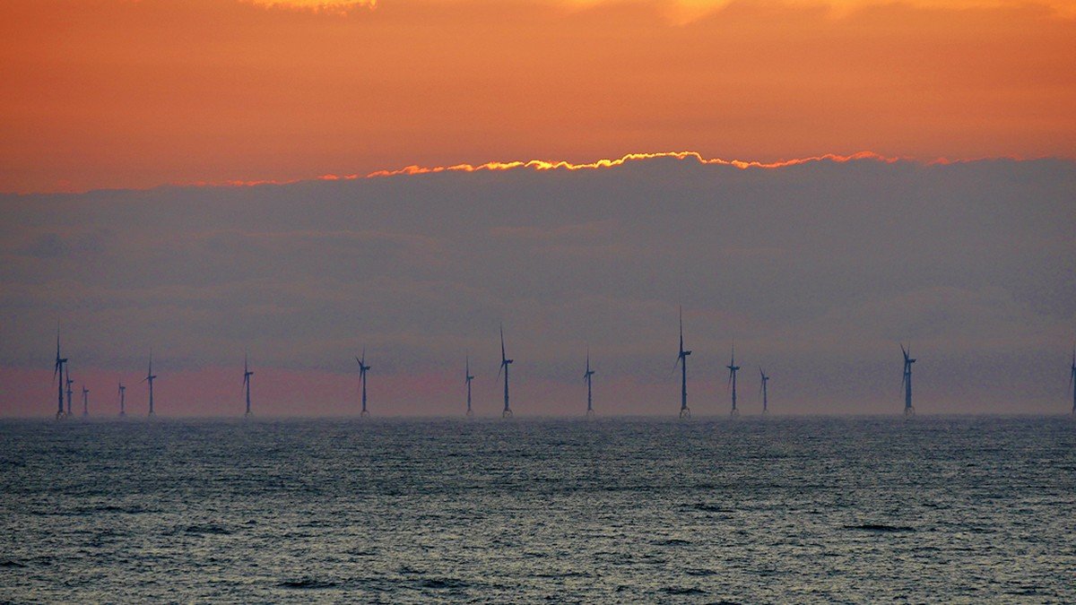 Offshore wind turbines turning in the sea against a clear horizon