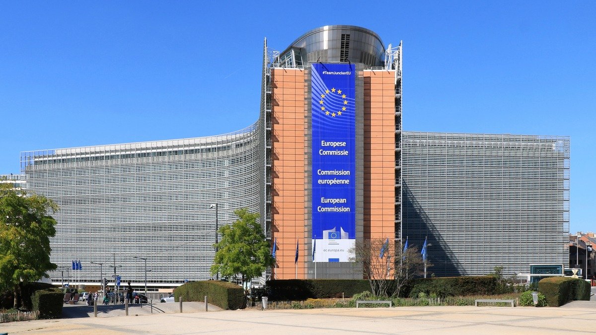 European Commission Berlaymont headquarters illuminated in Brussels with EU flags flying outside