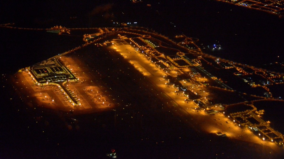 Beleuchtete Landebahn und Tower eines Verkehrsflughafens bei Nacht