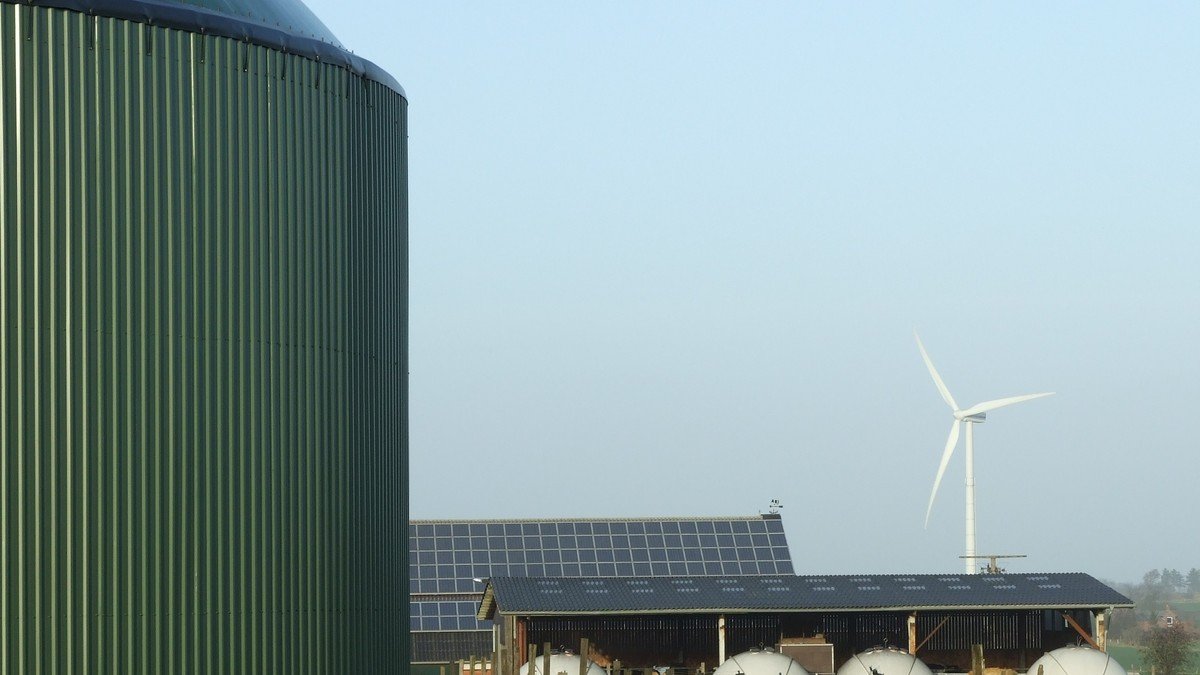 Large utility-scale solar photovoltaic array and modern wind turbines on a scenic hillside