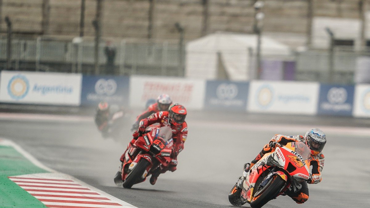MotoGP riders accelerating through a high-speed curve at the scenic Mandalika Circuit in Indonesia