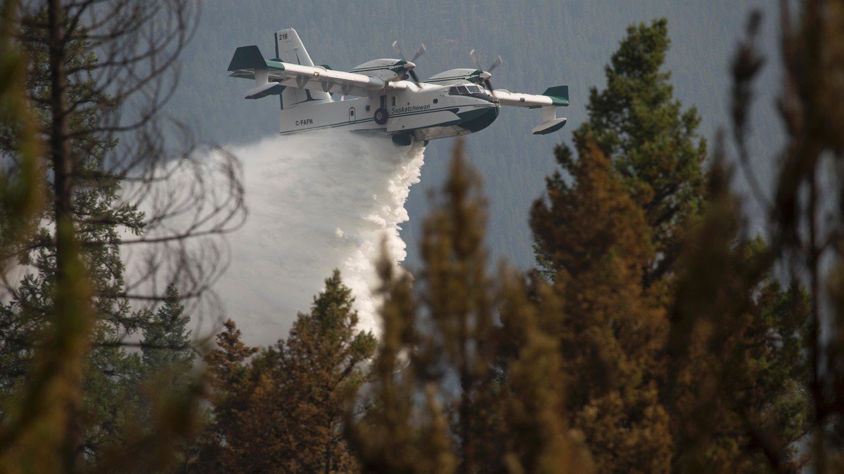 Canadair firefighting amphibious water bomber dropping water over a burning forest ridge