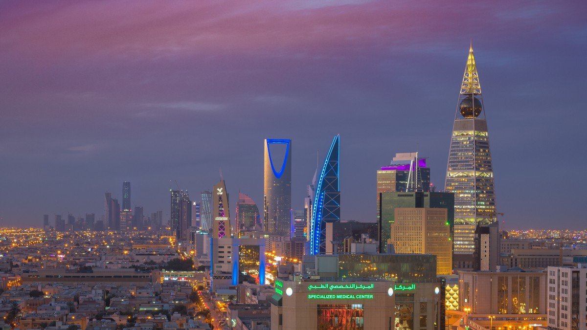 Illuminated Kingdom Centre tower and modern Riyadh skyline decorated in green for Saudi National Day