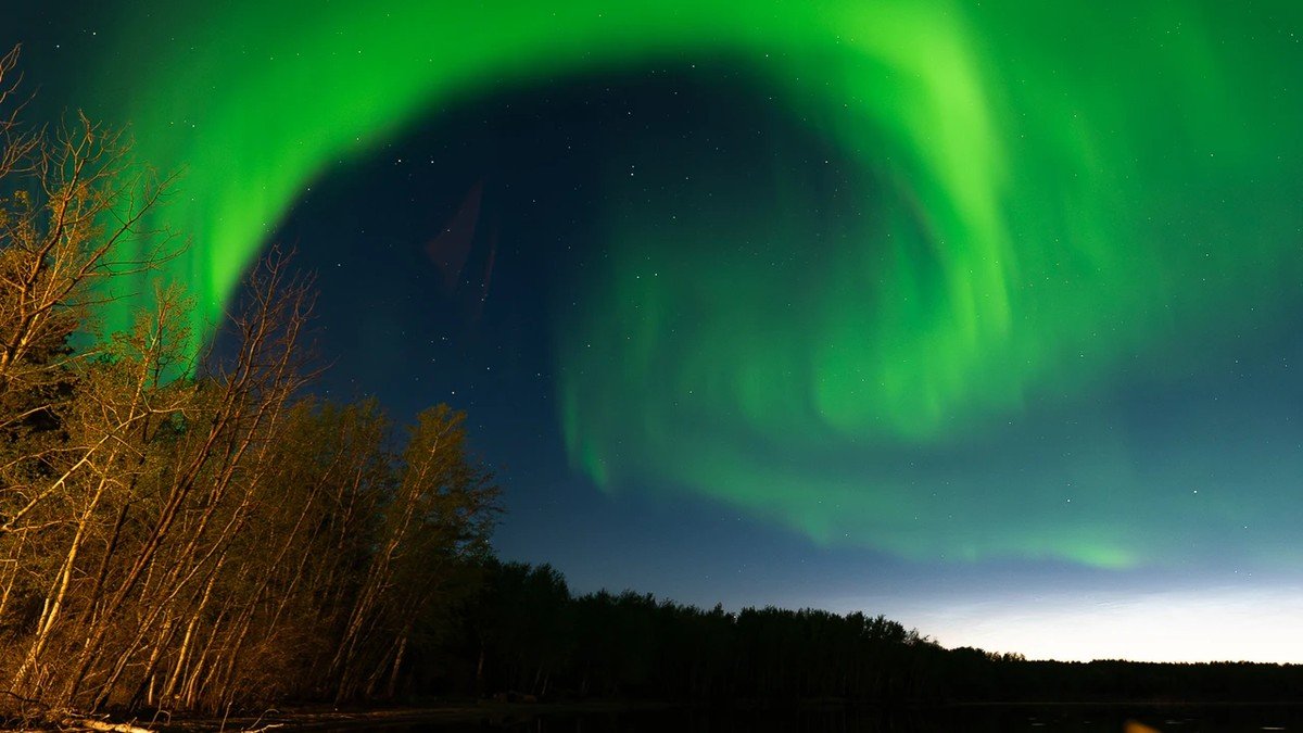 Leuchtend grüne und karminrote Polarlicht-Vorhänge am Nachthimmel während des schweren geomagnetischen G4-Sonnensturms