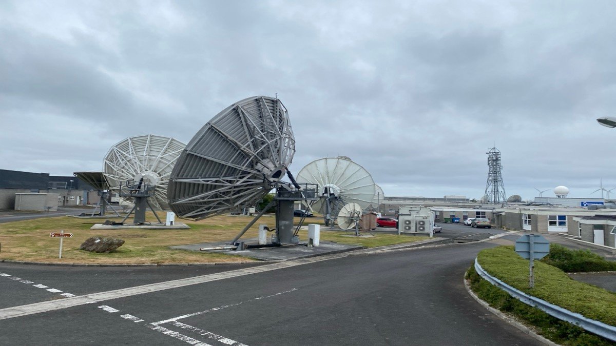 Array of large parabolic commercial satellite dish earth station antennas pointed toward the sky at a teleport facility