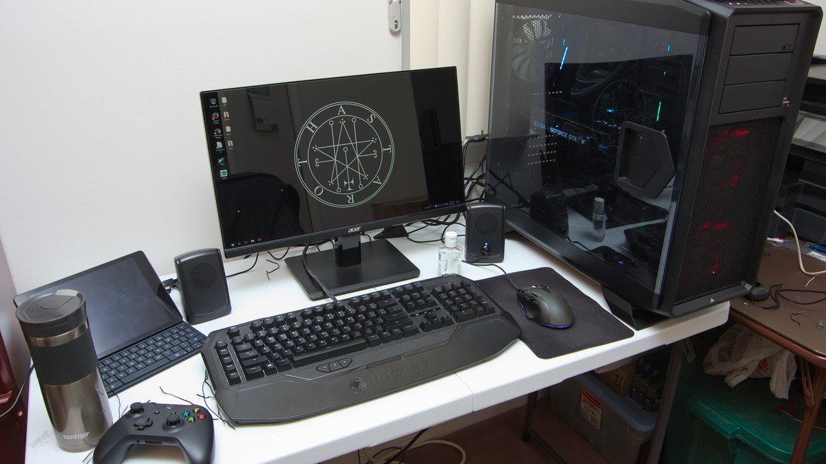 Modern PC gaming desk setup with illuminated keyboard, mouse, and monitor running games