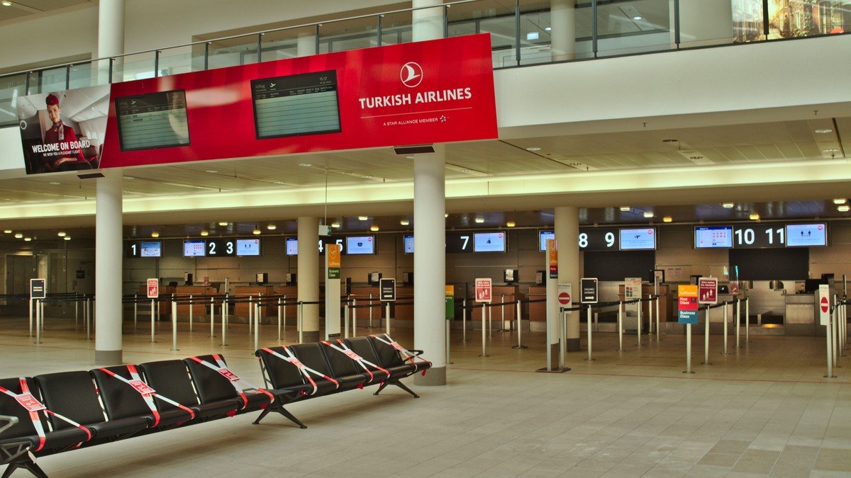 Belebtes Abflugterminal an einem internationalen Großflughafen mit Reisenden und Flugzielanzeigen